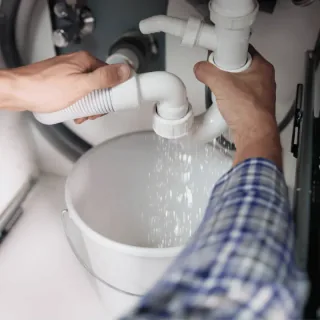 Water loopt uit een losgekoppelde afvoer in een opvangemmer