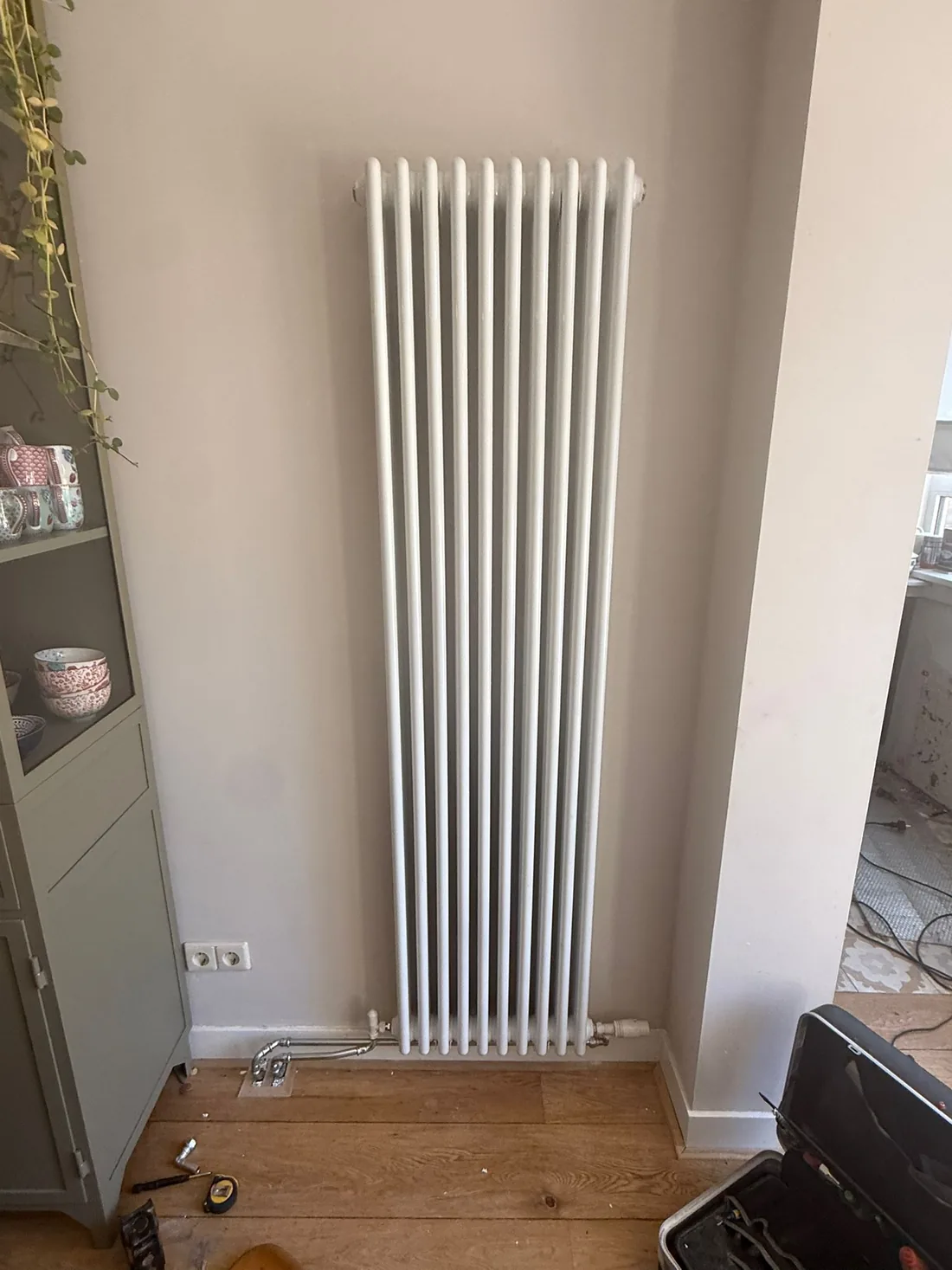 Vooraanzicht van de geplaatste witte kolomradiator met twaalf leden tegen een lichte wand