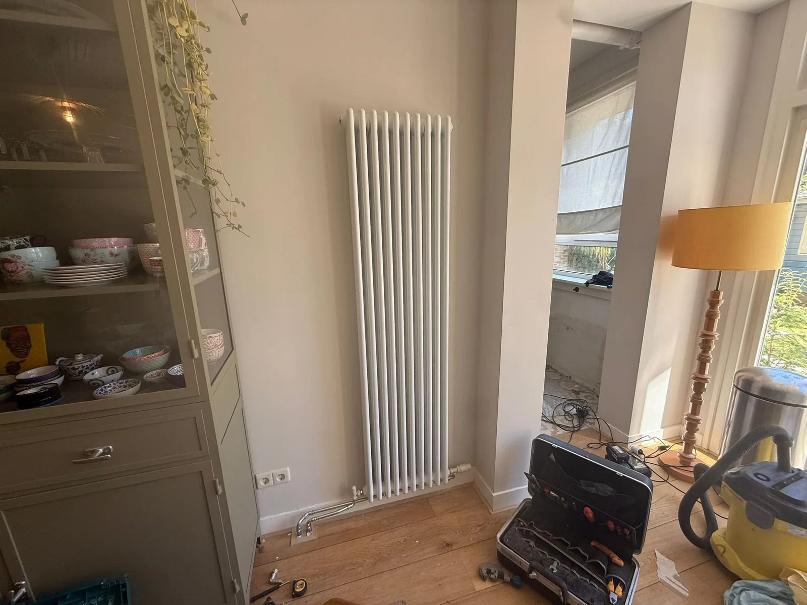 Witte verticale kolomradiator in de hoek van een woonkamer in een oud Amsterdams pand